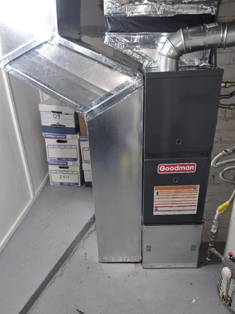 Goodman gas furnace installed in a Moore, OK rebuild-era home basement with new sheet-metal plenum and insulated supply ductwork