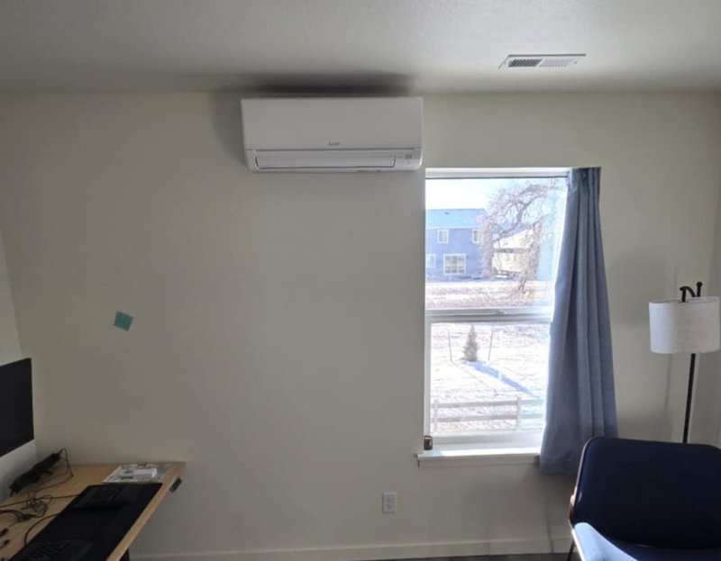 Mitsubishi ductless mini-split head unit installed in an Edmond, OK bedroom — clean wall mount, refrigerant line-set hidden