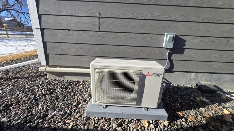 Mitsubishi Electric outdoor heat pump condenser — properly pad-mounted with service disconnect, the kind of install common in Canadian County new builds